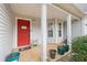 Inviting front porch featuring a bright red door, white columns, and decorative potted plants at 40 Berkshire Run, Covington, GA 30016