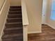 Carpeted staircase with white trim and natural light from the nearby window at 7467 Saint David St, Fairburn, GA 30213