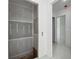 Hallway leads to an opening for a closet with shelves and a well-lit hallway with white tile floors at 1410 Lavista Ne Rd, Atlanta, GA 30324