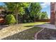 Grassy backyard with trees and bushes, framed by a red wooden fence at 480 Glenns Farm Way, Grayson, GA 30017