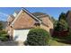 Side view of brick home, showcasing architectural details, manicured shrubbery, and two-car garage at 480 Glenns Farm Way, Grayson, GA 30017