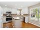 Bright kitchen features white cabinets, stainless steel appliances, and an island with hardwood floors at 480 Glenns Farm Way, Grayson, GA 30017