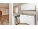 Bright kitchen with white cabinets, stainless steel dishwasher, stone countertops, and wood-look floors at 4893 Autumn Cir, Stone Mountain, GA 30088