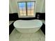 Modern white bathtub with chrome fixtures and a window with natural light at 3499 Lake Mill Rd, Buford, GA 30519