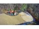 An aerial view of a backyard featuring a playground, volleyball court, trampoline, and wooded area at 3499 Lake Mill Rd, Buford, GA 30519