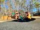 Wooden playset with slides and swings, set on a mulch bed in the backyard at 3499 Lake Mill Rd, Buford, GA 30519
