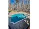 An aerial view of a rectangular pool with cool, clear water surrounded by a stone patio and trees at 3499 Lake Mill Rd, Buford, GA 30519