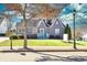 Charming home featuring a neatly manicured lawn, quaint front porch, mature trees, and a cheerful turquoise front door at 449 South Hill St., Buford, GA 30518