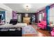 A modern reception area showcases hardwood floors, a fireplace, vibrant purple accent wall, and pink chairs at 449 South Hill St., Buford, GA 30518