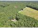 Aerial view showcases the homesite surrounded by mature trees and a field at 718 Fincher Rd, Covington, GA 30016