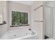 Bright bathroom with a soaking tub below a window overlooking trees, and a glass shower at 718 Fincher Rd, Covington, GA 30016