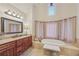 Luxurious bathroom featuring soaking tub, vanity with sink and framed mirror in a neutral palette at 9865 Buice Rd, Alpharetta, GA 30022