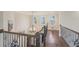 Hallway featuring decorative railing, hardwood floors and a chandelier in a neutral palette at 9865 Buice Rd, Alpharetta, GA 30022