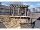 Outdoor bar area with a stone facade and dark-stained wooden pergola at 3015 Woodvale Ct, Alpharetta, GA 30022