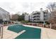 The community pool is covered with green safety cover, surrounded by concrete with gray siding of the apartments beyond at 602 Granville Ct, Sandy Springs, GA 30328