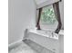 Bright bathroom featuring a large white tub with a window and brown curtains for natural light and privacy at 907 Fox Croft Pl, Canton, GA 30114