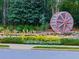 Beautiful entrance to Bridge Mill, featuring a decorative water wheel and lush landscaping and colorful flowers at 907 Fox Croft Pl, Canton, GA 30114