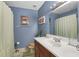 This bathroom features blue walls, a white sink and commode, and a shower at 1600 Yukon Ct, Atlanta, GA 30349