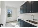 Bright laundry room boasts navy cabinets, a utility sink, white countertops, and a window with a view at 1445 Ashwoody Ne Ct, Atlanta, GA 30319