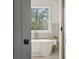 Luxurious bathroom featuring a soaking tub, elegant fixtures, and a view of the outdoors through a large window at 1788 Piper Se Cir, Atlanta, GA 30316