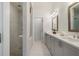 Modern bathroom showcasing double vanity, granite counters, decorative mirrors and tiled shower with glass door at 2390 Edgar Park Pl # 102, Duluth, GA 30096