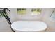 Bright bathroom featuring a modern soaking tub, black fixtures, and large windows overlooking the fenced in pool at 805 Wesley Oak Rd, Atlanta, GA 30328