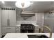Kitchen featuring stainless steel stove, pot filler, white tile, white cabinets and white stone counter tops at 805 Wesley Oak Rd, Sandy Springs, GA 30328