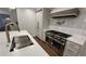 Kitchen featuring a stainless steel stove with white tiling, a pot filler, white cabinets, and stone counter tops at 805 Wesley Oak Rd, Sandy Springs, GA 30328