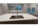 Kitchen island with stainless steel sink and golden faucet against cabinets and shelves and large windows at 805 Wesley Oak Rd, Sandy Springs, GA 30328