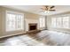 Bright living room features a cozy brick fireplace, large windows, and modern wood-look flooring at 145 Price Hills Ct, Sugar Hill, GA 30518