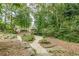 Scenic backyard featuring a winding gravel pathway, mature trees, rock features, and lush landscaping at 180 Winecoff Dr, Fayetteville, GA 30214