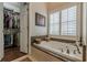 Bathroom featuring a soaking tub, walk-in closet, and a large window for natural lighting at 180 Winecoff Dr, Fayetteville, GA 30214