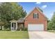 Brick home featuring a two-car garage, manicured lawn, and mature trees at 180 Winecoff Dr, Fayetteville, GA 30214