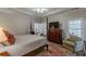 Bright main bedroom featuring a bed, tv on bureau and a sitting chair with natural light streaming in at 180 Winecoff Dr, Fayetteville, GA 30214