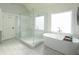 Luxurious bathroom featuring a large soaking tub, glass enclosed shower with a bench, and bright, airy space at 4095 Copper Leaf Ln, Cumming, GA 30040