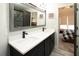 Modern bathroom featuring double sinks, black faucets, a gray wood-trimmed mirror, and a doorway into the primary bedroom at 4095 Copper Leaf Ln, Cumming, GA 30040