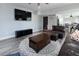 Open concept living room with dark couches, rug, hardwood floors and a TV at 4095 Copper Leaf Ln, Cumming, GA 30040