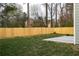 Large backyard with a wood privacy fence, green lawn, and a small concrete patio at 6242 Marbut Farms Ln, Lithonia, GA 30058