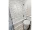 Bathroom featuring a tub-shower with decorative marble tiles, a toilet, and modern gray paint at 6242 Marbut Farms Ln, Lithonia, GA 30058