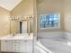 This primary bathroom features a double vanity, large mirror, and soaking tub under a window at 155 Mine Run, Fayetteville, GA 30215