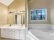 This primary bathroom features a double vanity, large mirror, and soaking tub under a window at 155 Mine Run, Fayetteville, GA 30215