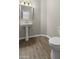 A well-lit bathroom with a pedestal sink, a large mirror, and wood-look flooring at 1202 Charleston Ct Cir, Woodstock, GA 30188