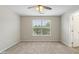 Spacious carpeted bedroom featuring a ceiling fan and bright window with natural light at 1202 Charleston Ct Cir, Woodstock, GA 30188