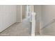 Well-lit hallway with neutral carpet and white doors, stairs going down, and view of rooms at 1202 Charleston Ct Cir, Woodstock, GA 30188