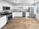 Bright kitchen featuring white cabinets, stainless steel appliances, and wood grain flooring at 61 Barrington Pl, Marietta, GA 30066