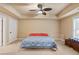 Carpeted bedroom with ceiling fan, tray ceiling, and natural light from the windows at 3130 Kates Nw Way, Kennesaw, GA 30152