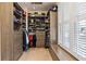 Well-organized walk-in closet featuring custom shelves, drawers, and bench seat by window at 3130 Kates Nw Way, Kennesaw, GA 30152