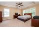 Spacious bedroom with tray ceilings and a ceiling fan with a wooded bed frame at 3008 Stockbridge Way, Dacula, GA 30019