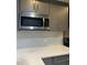 Modern kitchen featuring stainless steel microwave, gray cabinets, white countertop, and gray backsplash at 3008 Stockbridge Way, Dacula, GA 30019