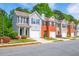 Street view of townhouses with well-manicured lawns, colorful flowers, and garages, set against a lush green backdrop at 485 Lantern Wood Dr, Scottdale, GA 30079